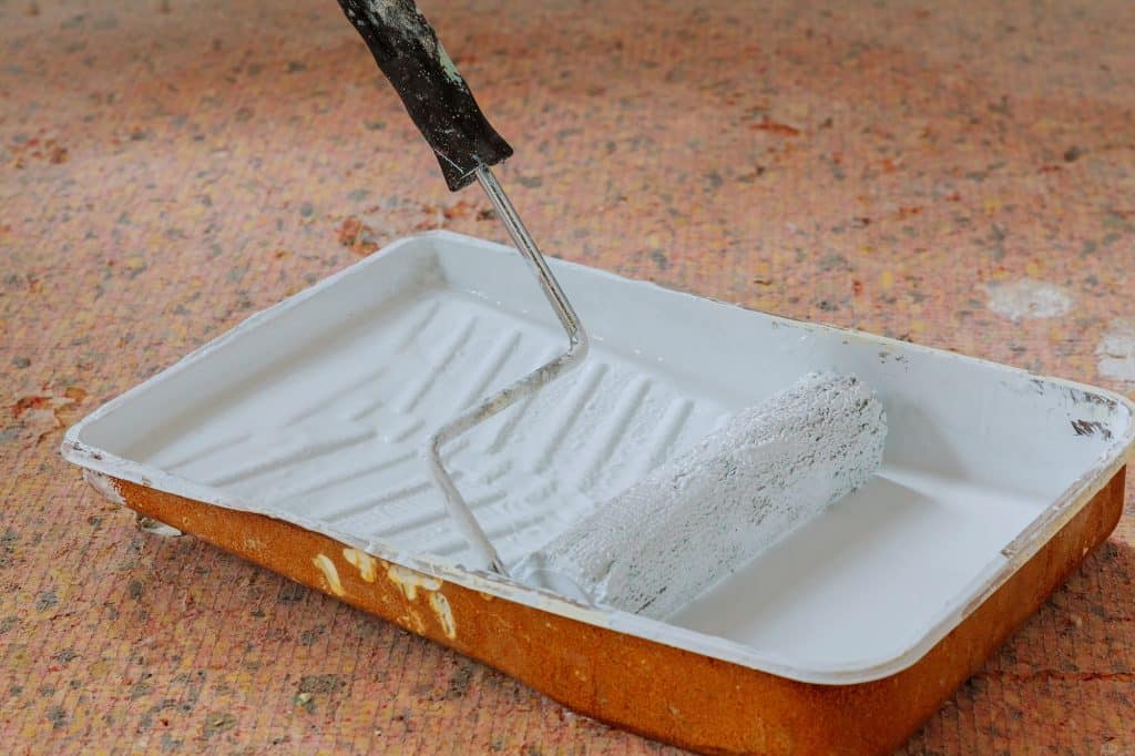 Expert Interior and Exterior Painting | King & Pierce Counties Realistic image of paint pan and roller on drop cloth during painting project